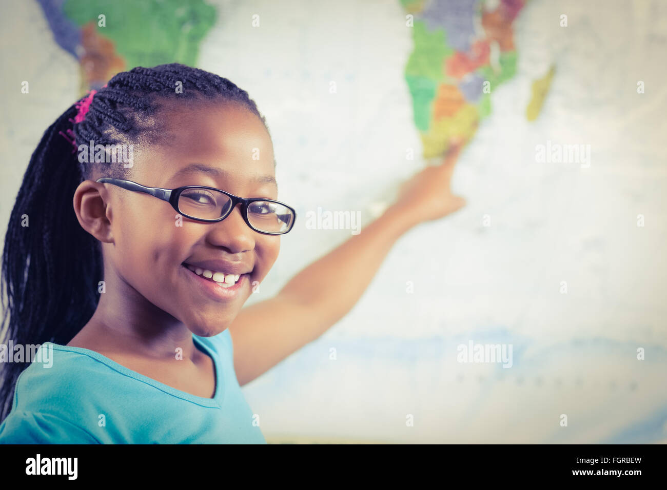 Smiling pupil pointing on world map in a classroom Stock Photo - Alamy