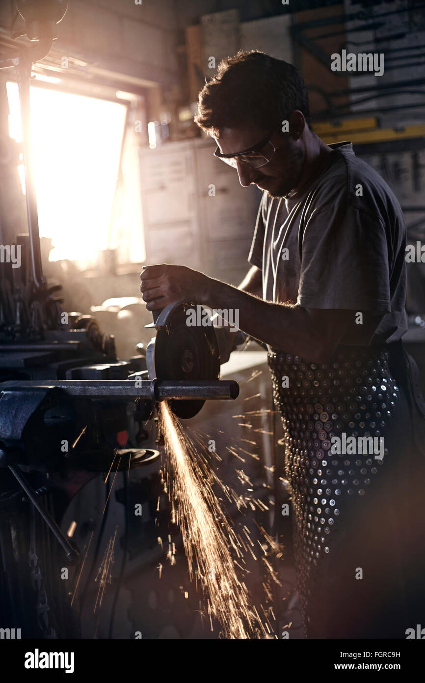 Blacksmith using saw in forge Stock Photo