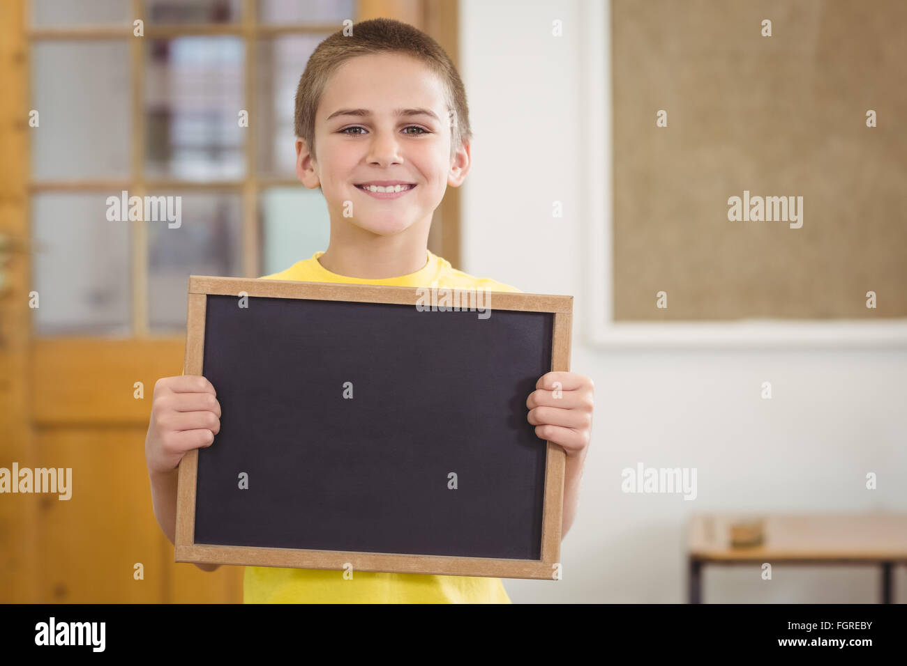 Smiling pupil holding chalkboard in a classroom Stock Photo - Alamy