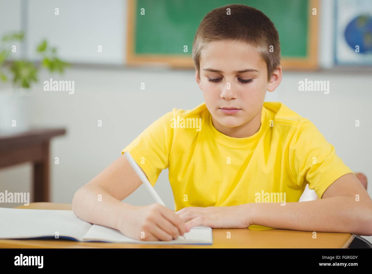 Concentrated pupil working at his desk in a classroom Stock Photo - Alamy