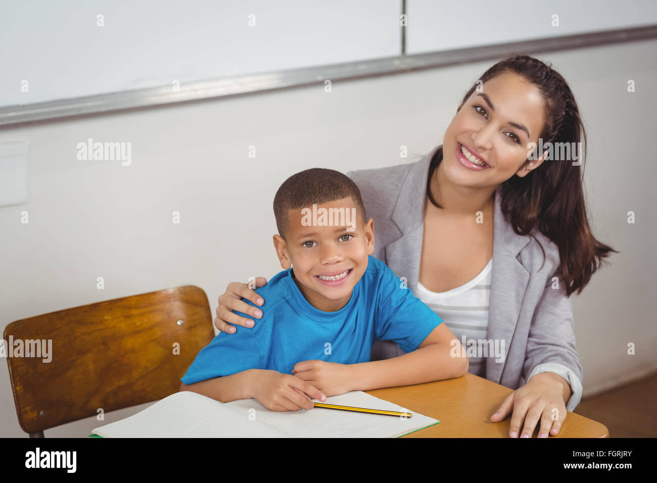 Smiling teacher and her pupil sitting at desk Stock Photo - Alamy