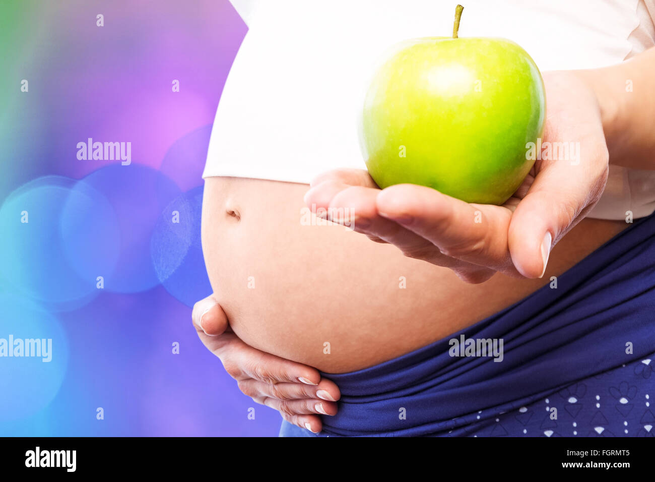 Composite image of pregnant woman holding green apple Stock Photo