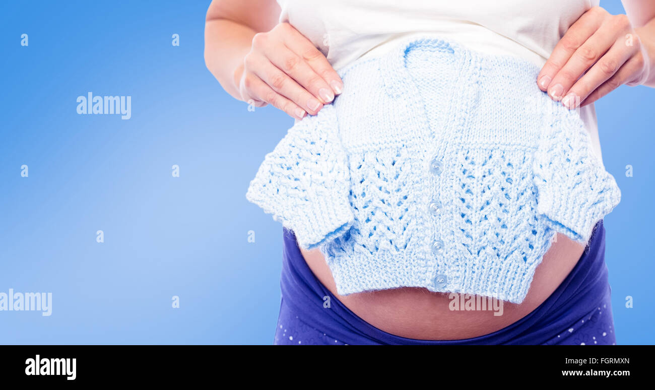 Composite image of pregnant woman holding baby clothes Stock Photo