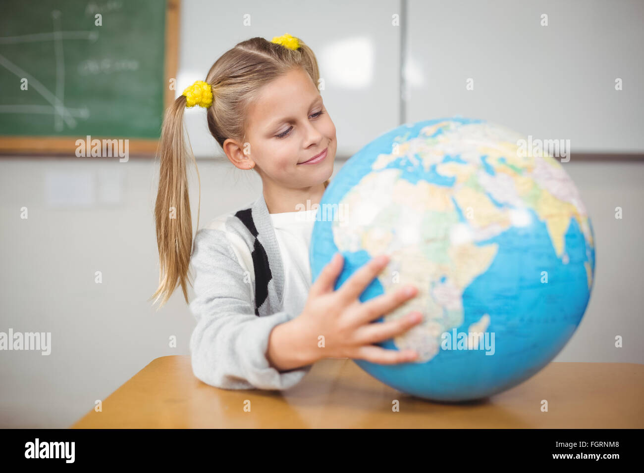 Cute pupil holding globe in a classroom Stock Photo - Alamy
