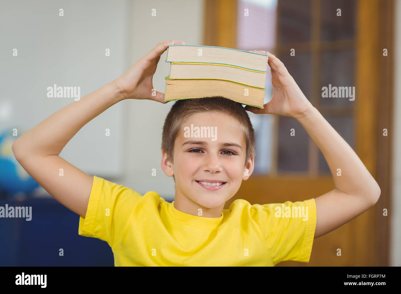 Smiling pupil balancing books on head in a classroom Stock Photo - Alamy