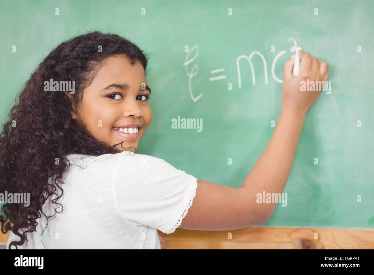 Smiling pupil writing on chalkboard in a classroom Stock Photo - Alamy