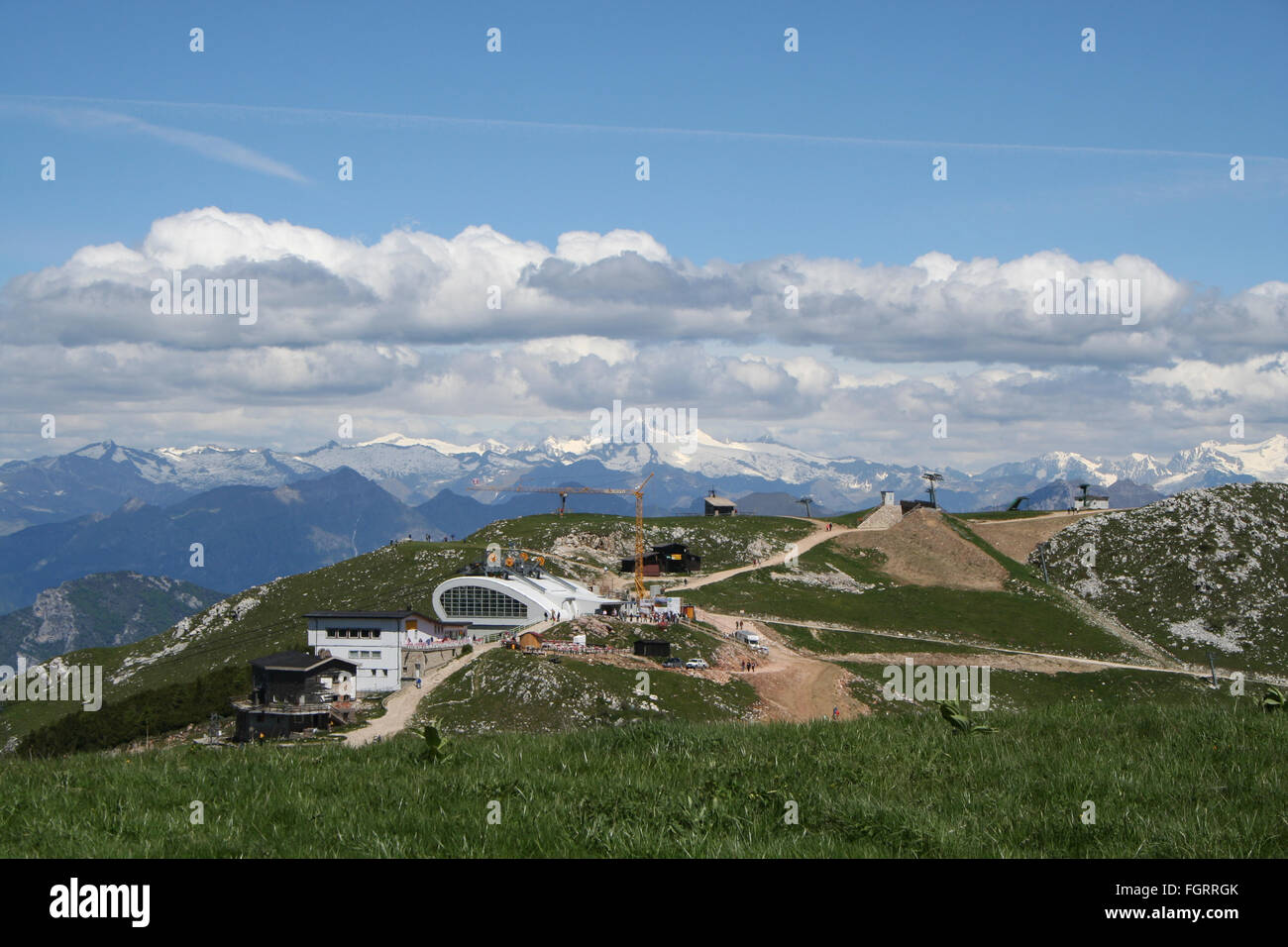 Construction of the modern Monte Baldo cable car station in the Italian Alps. Snow covered peaks line the background. Stock Photo