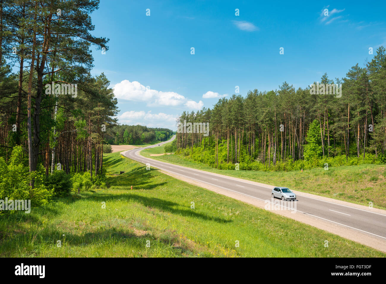 Single car on country road in forest in Belarus. Blue sky with clouds in  background. Beautiful and sunny summer or spring day. R Stock Photo - Alamy