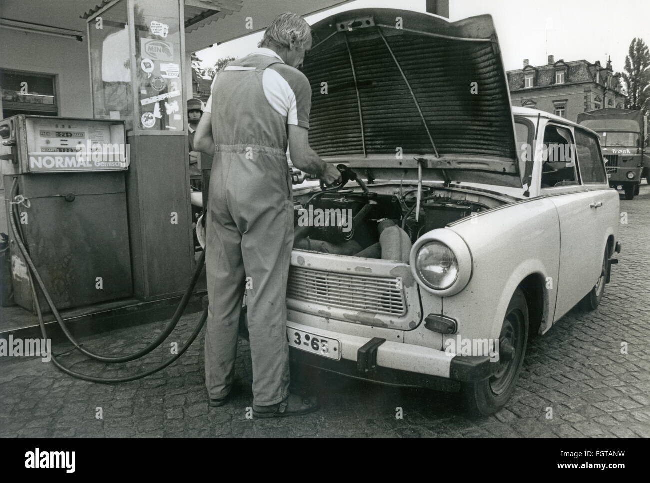 transport / transportation,car,filling station attendant refuelling Trabant,Trabi Kombi 601,Dresden,Germany,East-Germany,July 1990,tank under the hood,gas station,petrol stations,gas stations,filling station,fuelling station,filling stations,fuelling stations,service station,service stations,petrol pump,gas pump,petrol pumps,gas pumps,fuel pump,gasoline pump,fuelling,lean gas mixture,oil gas combination,two-stroke mix,Minol,profession,professions,work,works,engine bonnet opened,Saxony,turning points,turning point,GDR car,GD,Additional-Rights-Clearences-Not Available Stock Photo