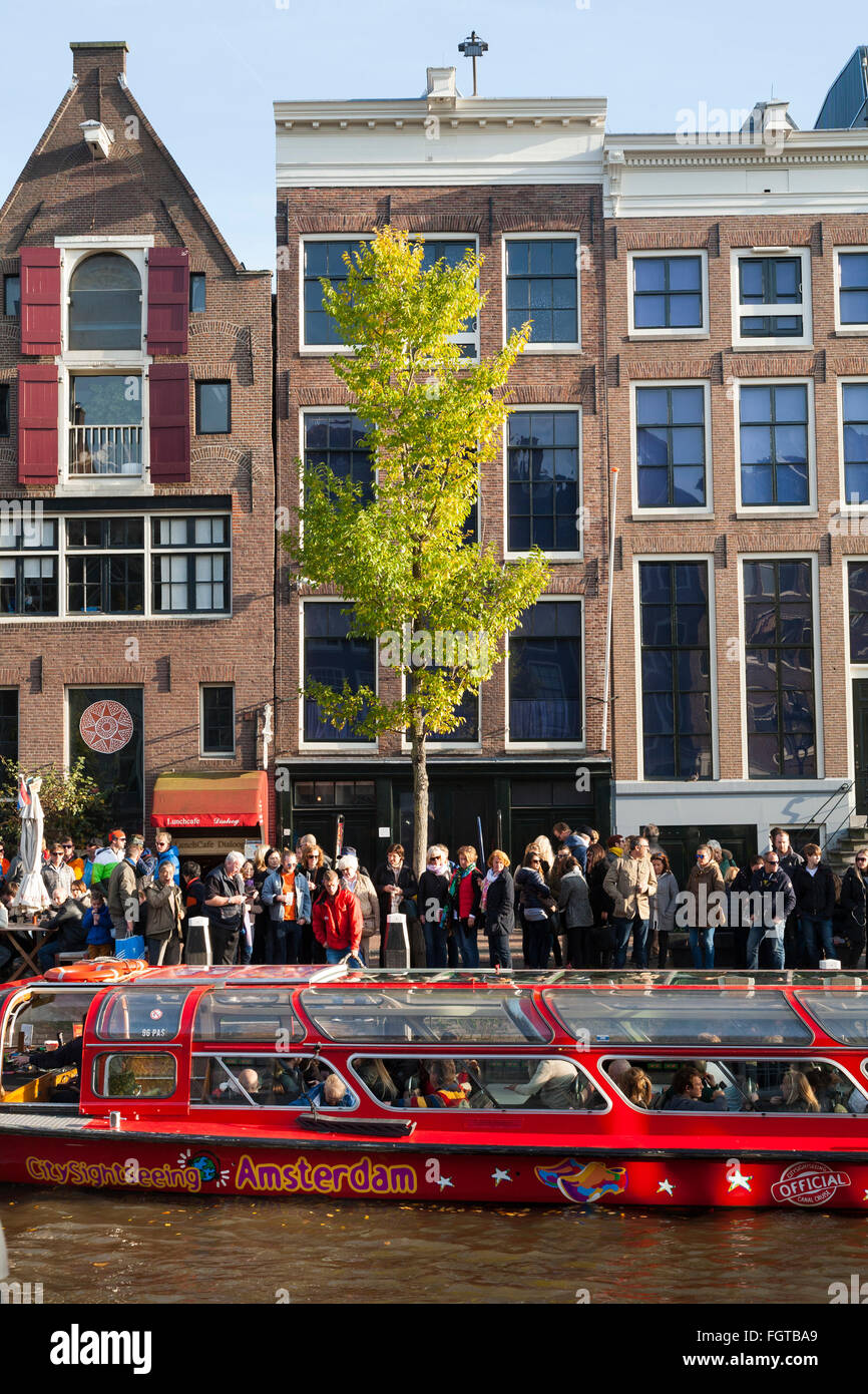 Tourist sight seeing boat with tourists / visitors in front of Anne Frank 's House / museum in Amsterdam Holland The Netherlands Stock Photo