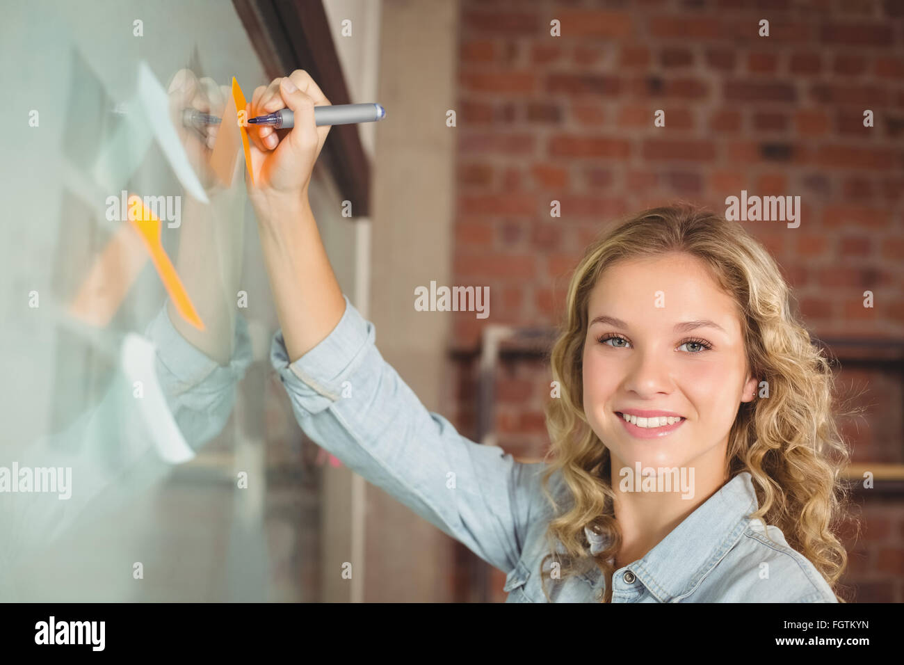 Portrait of businesswoman writing on sticky notes in office Stock Photo ...