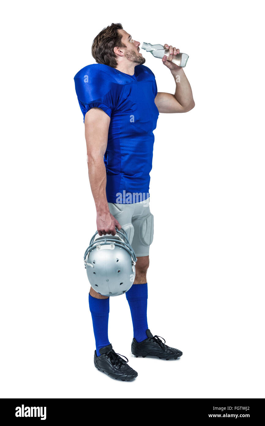 Full length of American football player holding helmet while drinking