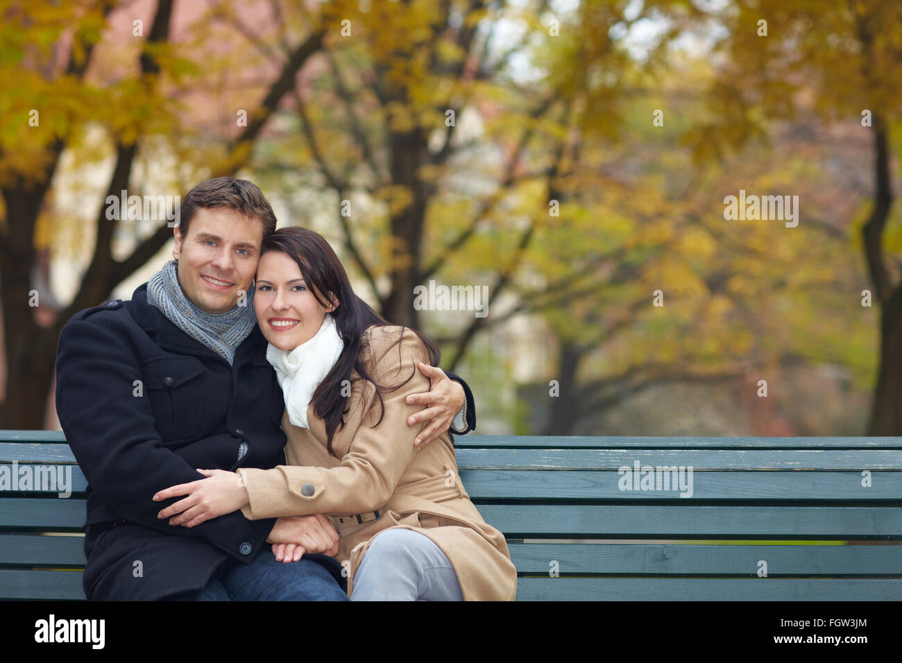 Happy smiling couple on park bench in fall Stock Photo - Alamy