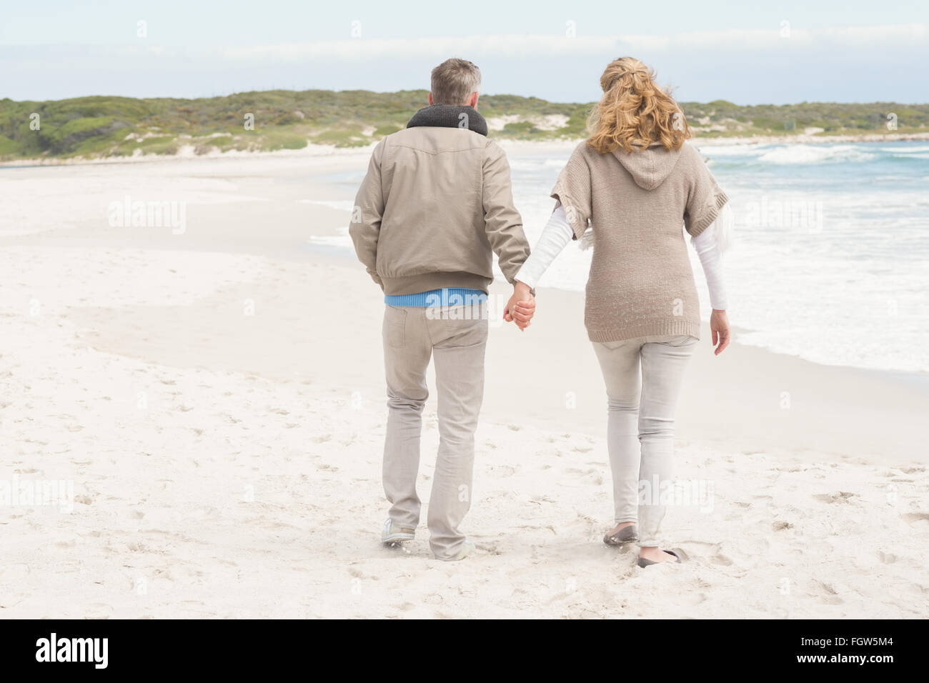 Happy couple holding hands while walking Stock Photo - Alamy