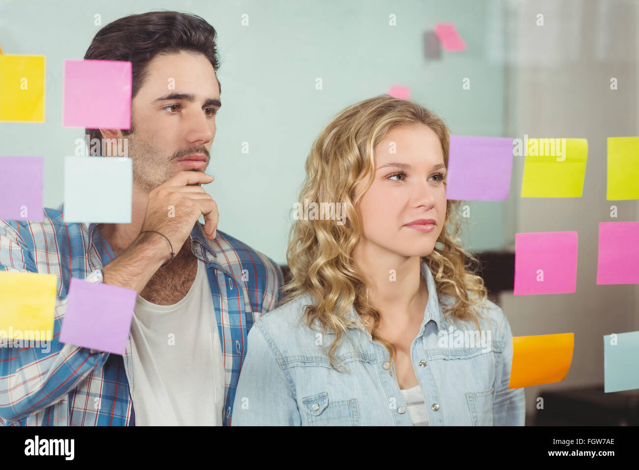 Colleagues looking at notes on glass in office Stock Photo - Alamy
