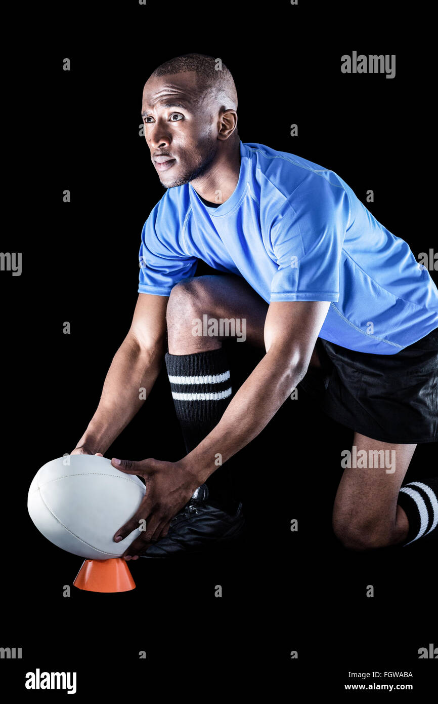 Sportsman looking away while keeping rugby ball on kicking tee Stock