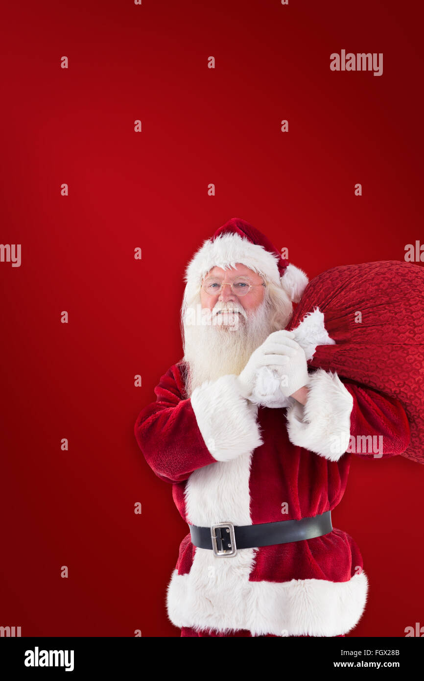 Composite image of santa carries his red bag and smiles Stock Photo - Alamy