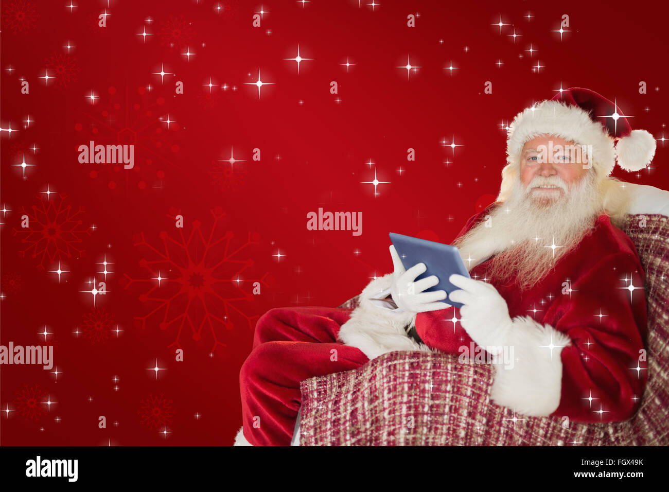 Composite image of smiling santa using tablet on the armchair Stock ...
