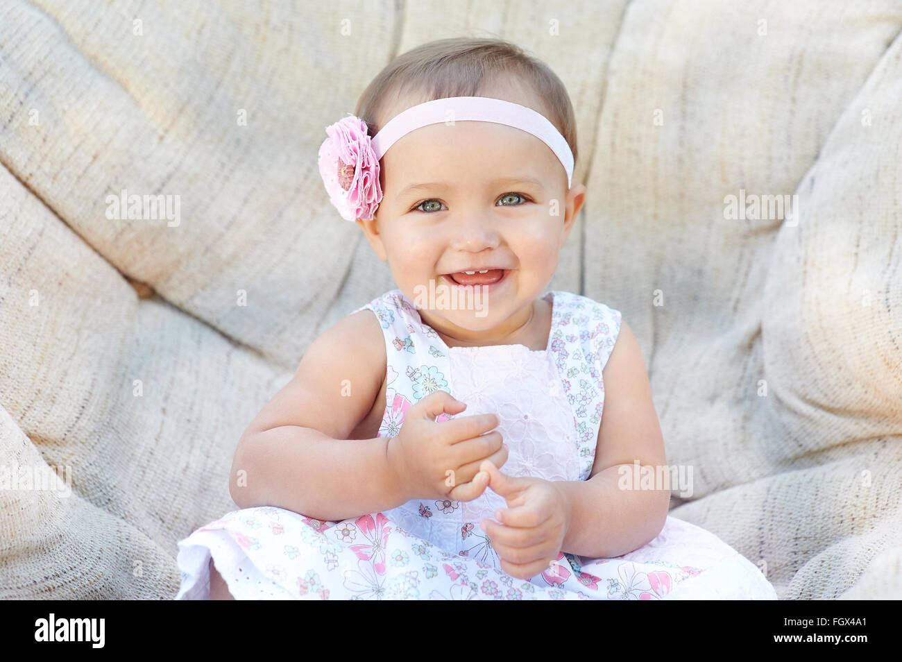 Cheerful little girl sitting on the white chair Stock Photo