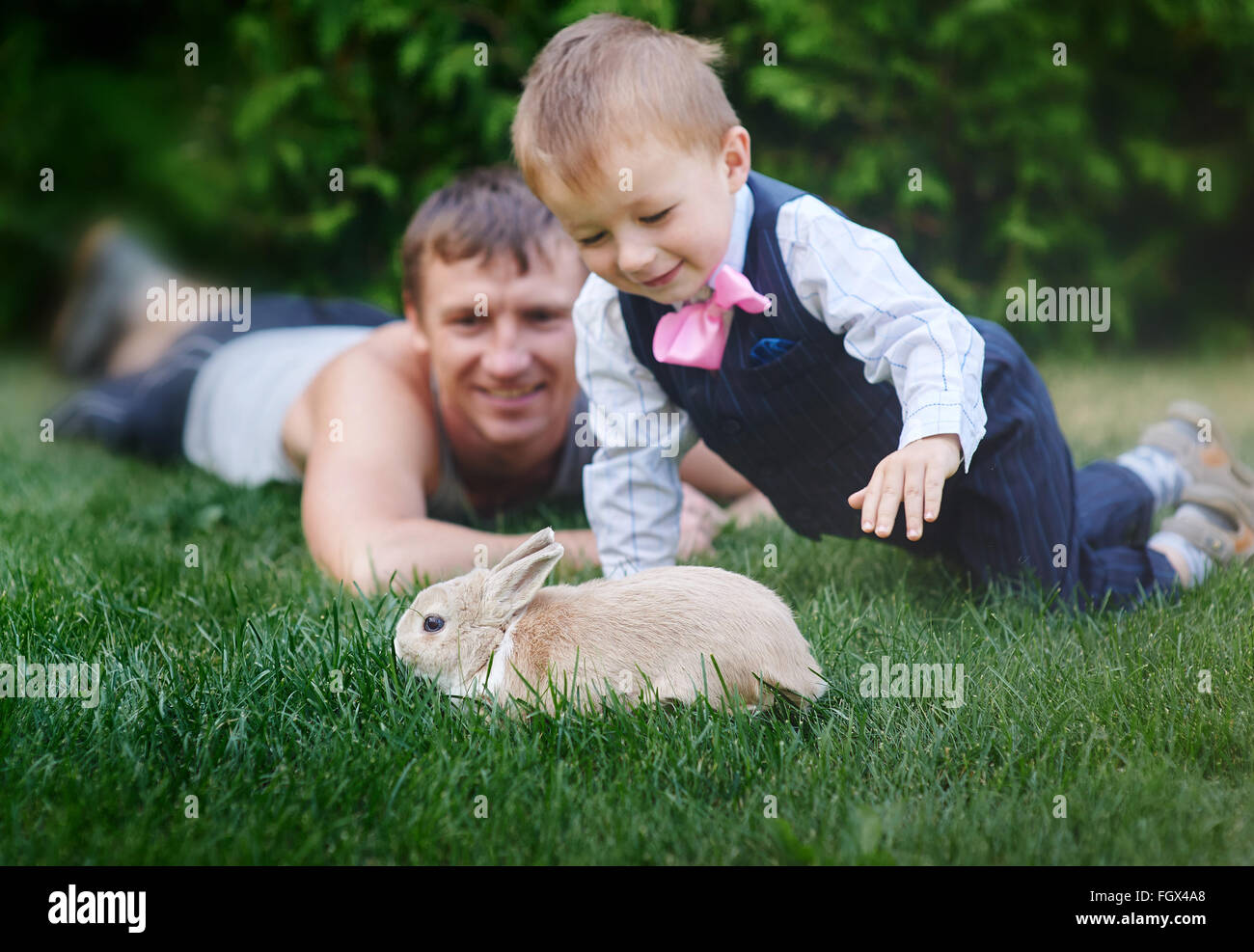 little boy with his father playing with a rabbit on the grass Stock Photo