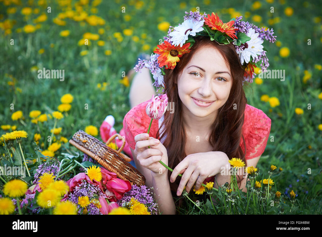 happy woman with wreath lying on a meadow with a bouquet of flowers Stock Photo