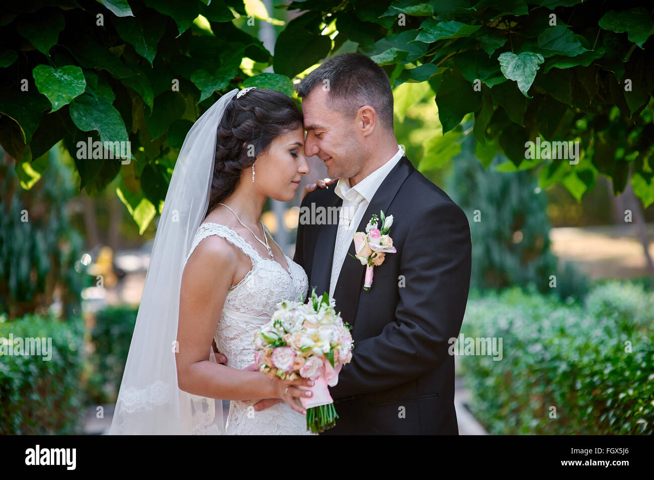 bride and groom with a bouquet of walking in the summer park Stock Photo