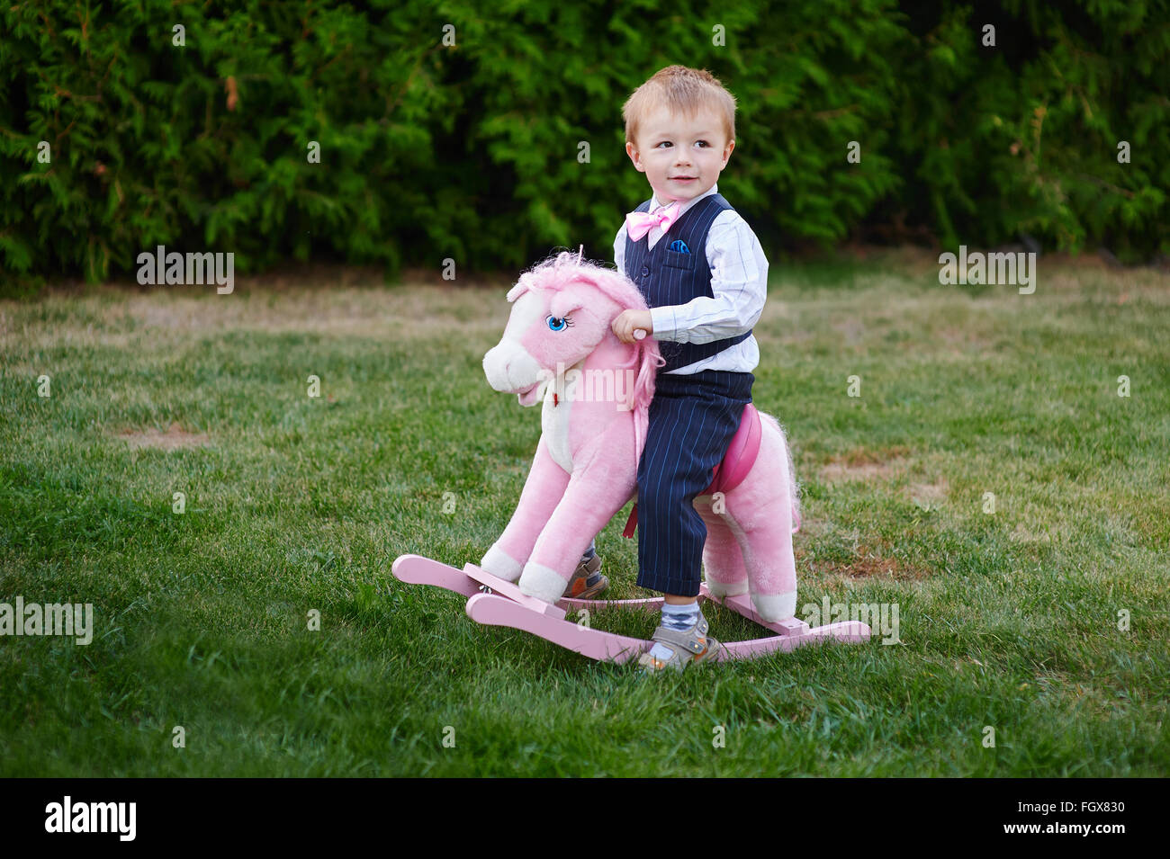 Baby boy playing with horse on playground in park Stock Photo