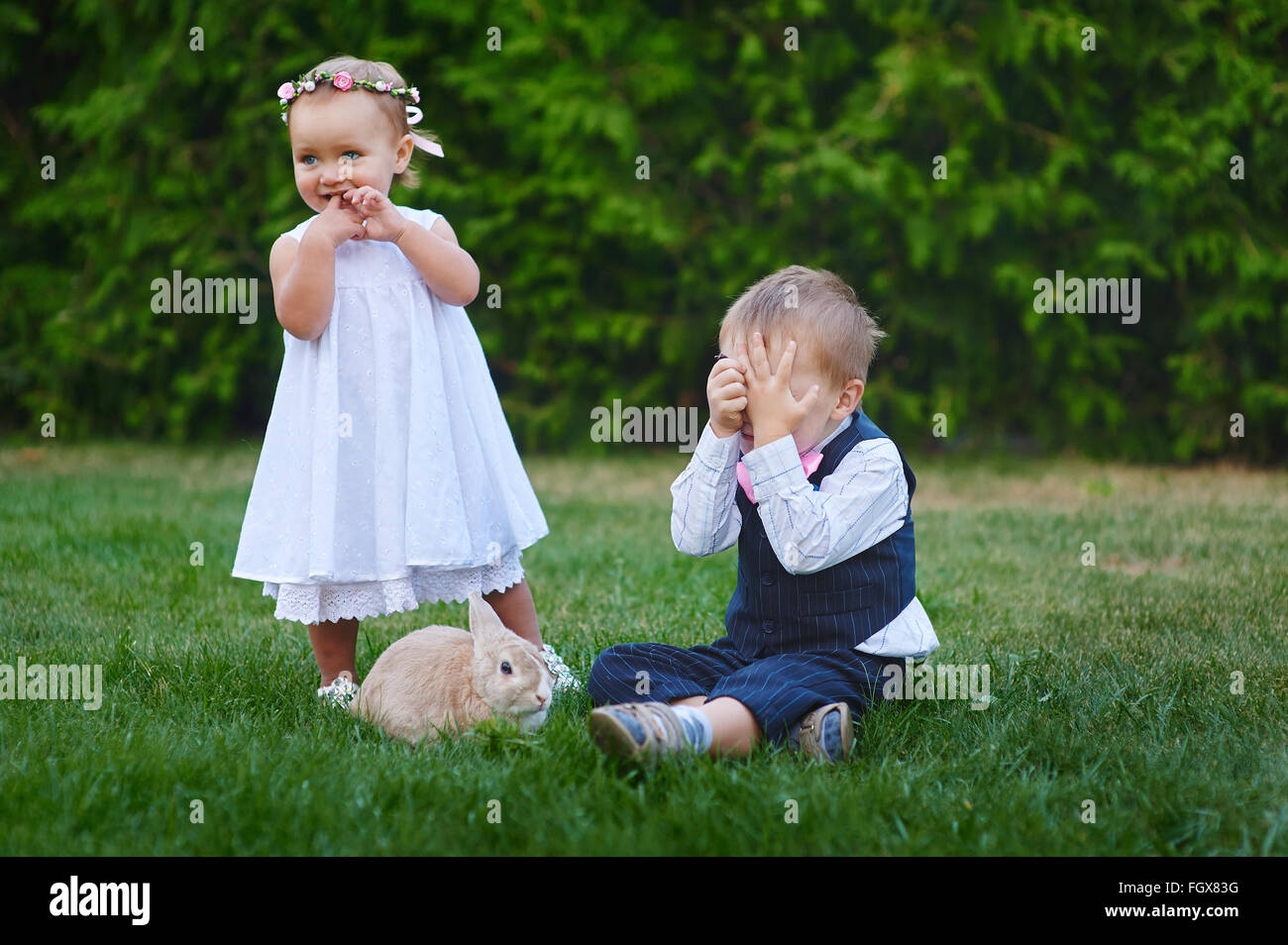 little boy with the girl and rabbit playing in the grass Stock Photo