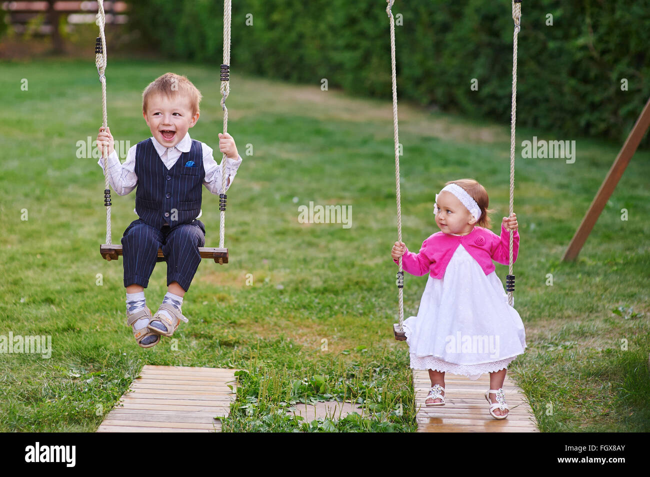 Little boy and girl ride in the park on a swing Stock Photo