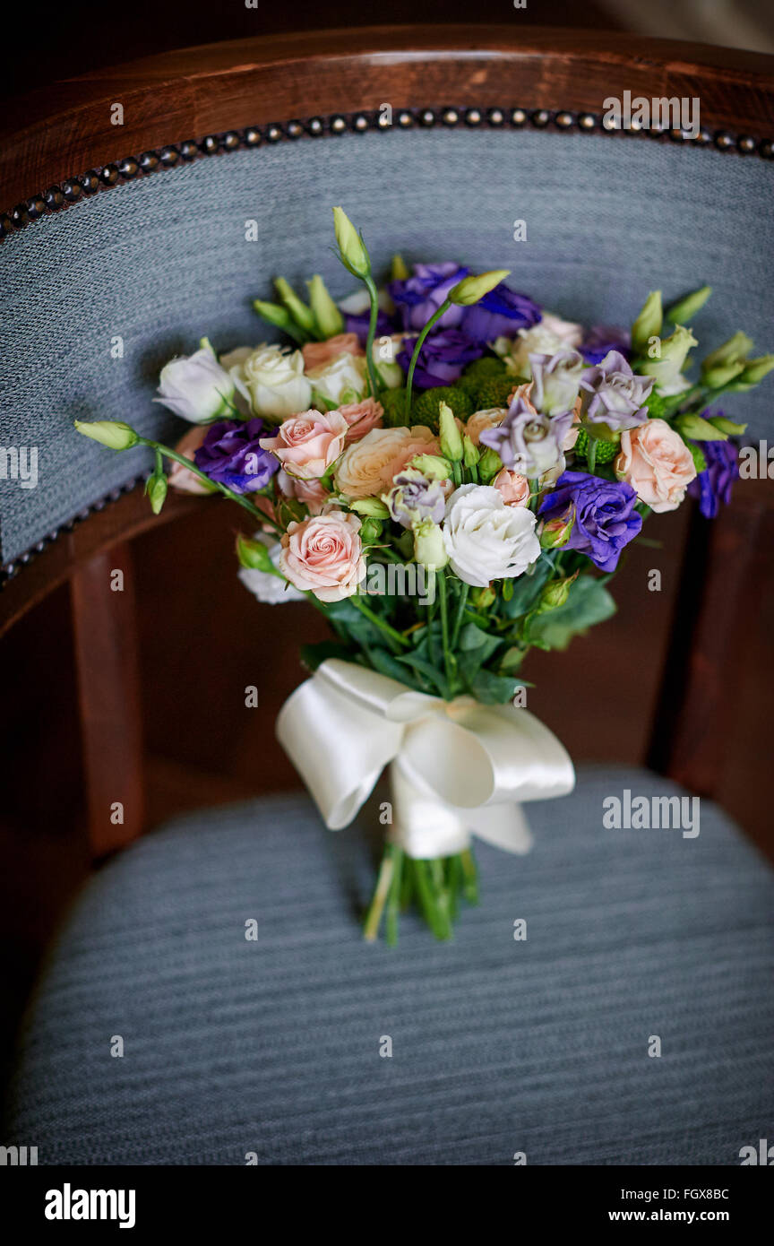 Pink and purple flowers in wedding bridal bouquet on chair Stock Photo