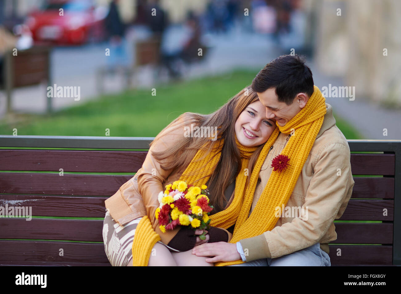 love couple sitting on a bench with a bouquet of flowers Stock Photo