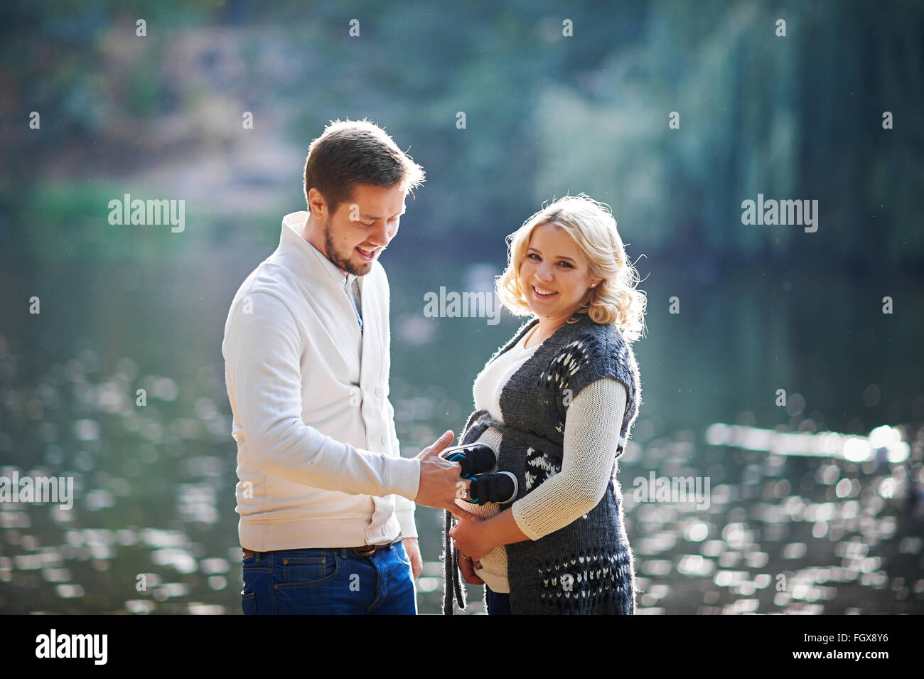 Happy pregnant women and her husband during the walk with a man near the lake Stock Photo