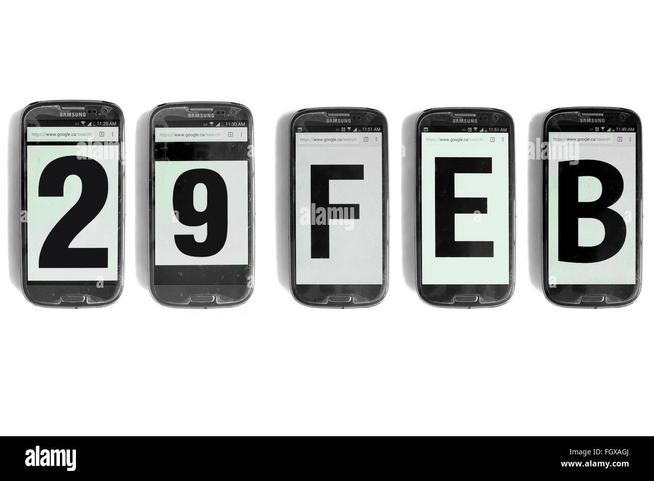 29 Feb written on the screens of smartphones photographed against a white background. Stock Photo