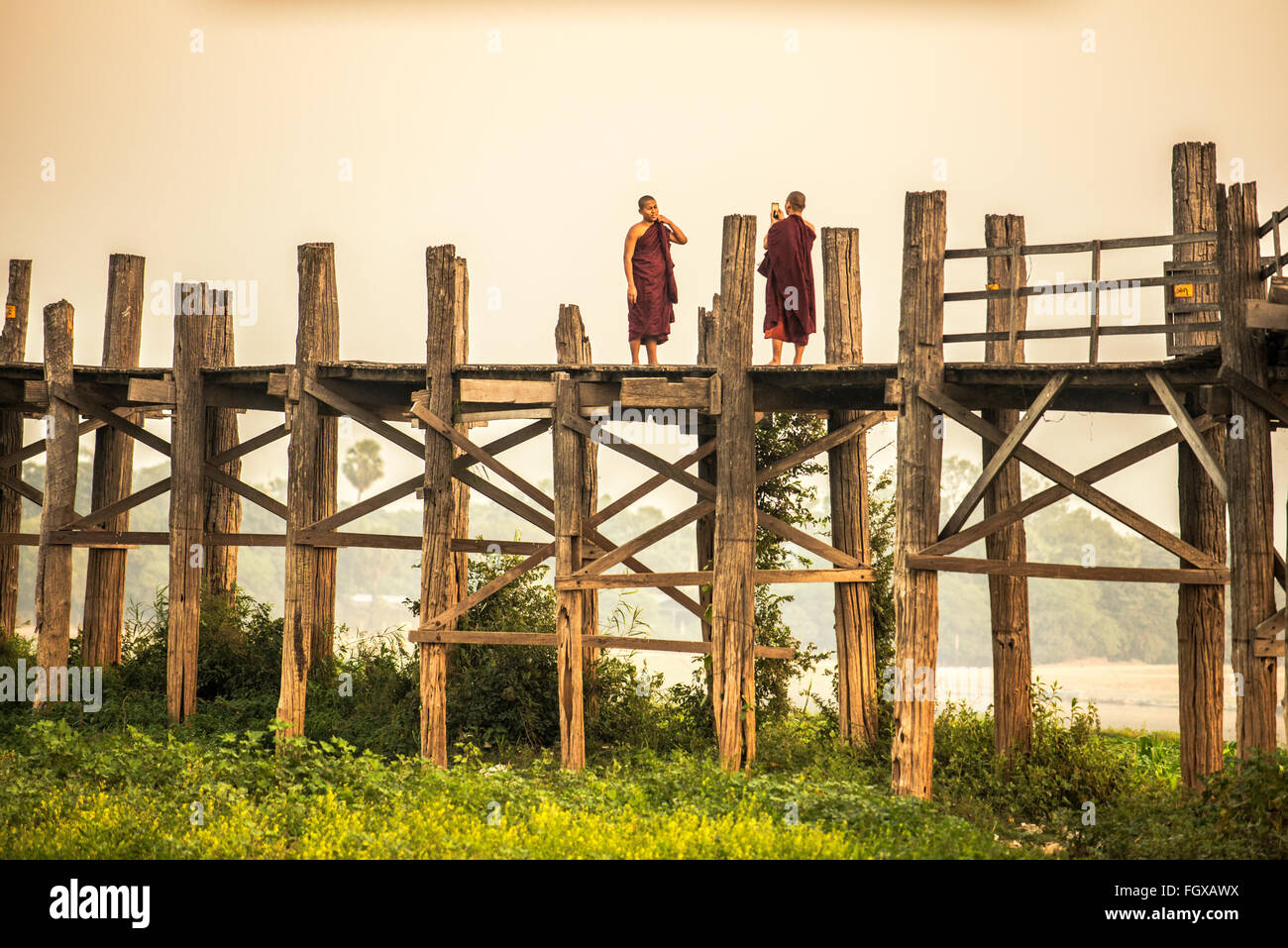 Two buddhist monks taking photograph with mobile phone on  the historic wooden U Bein Bridge Stock Photo