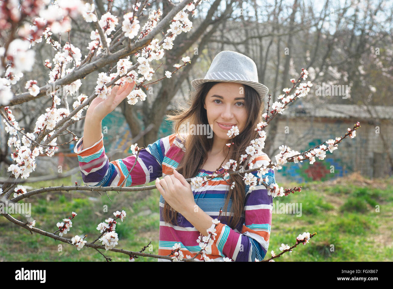 Beautiful happy young woman enjoying smell in a flowering spring garden Stock Photo