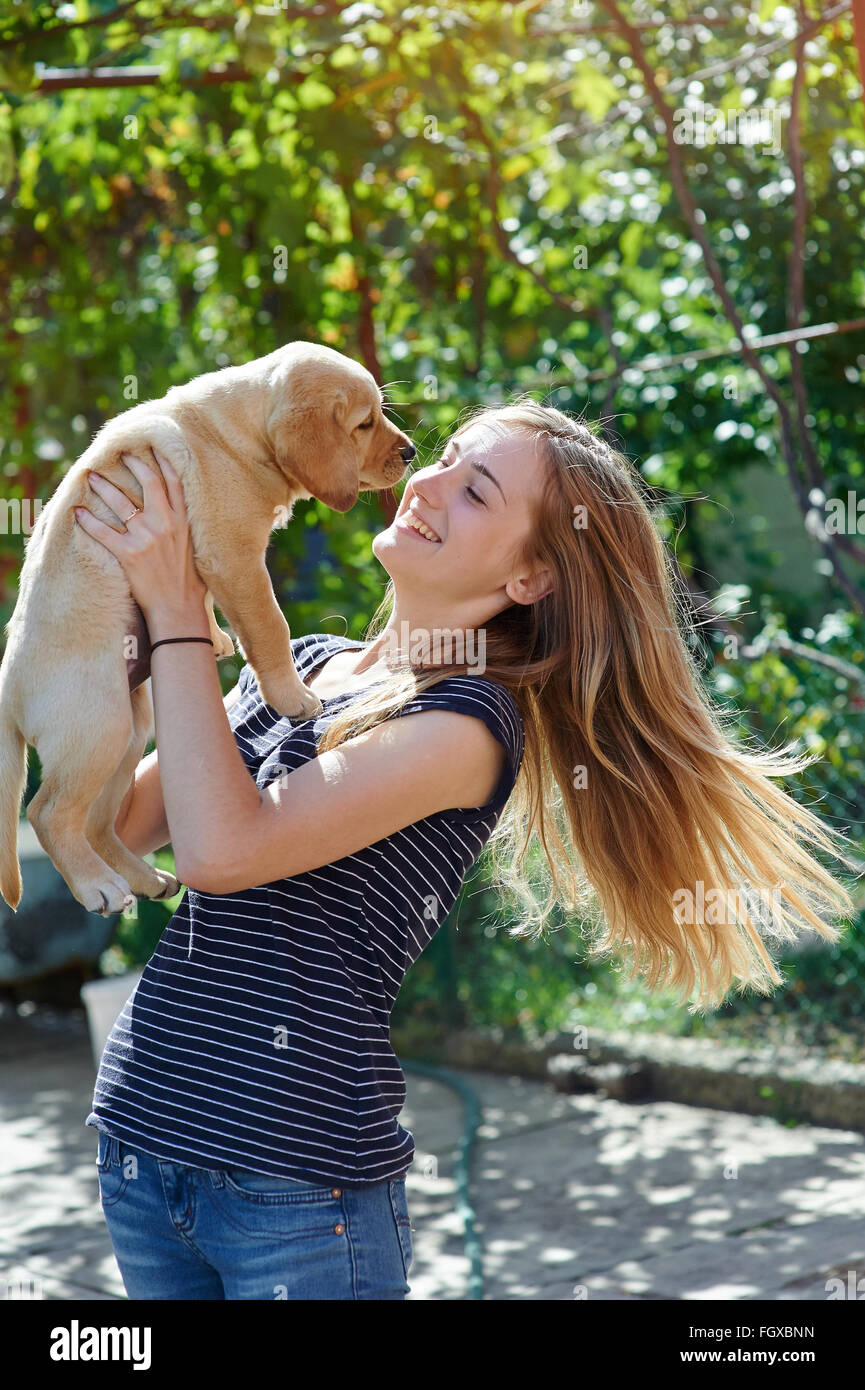 Portrait of Young woman holding on hands puppy Labrador Stock Photo