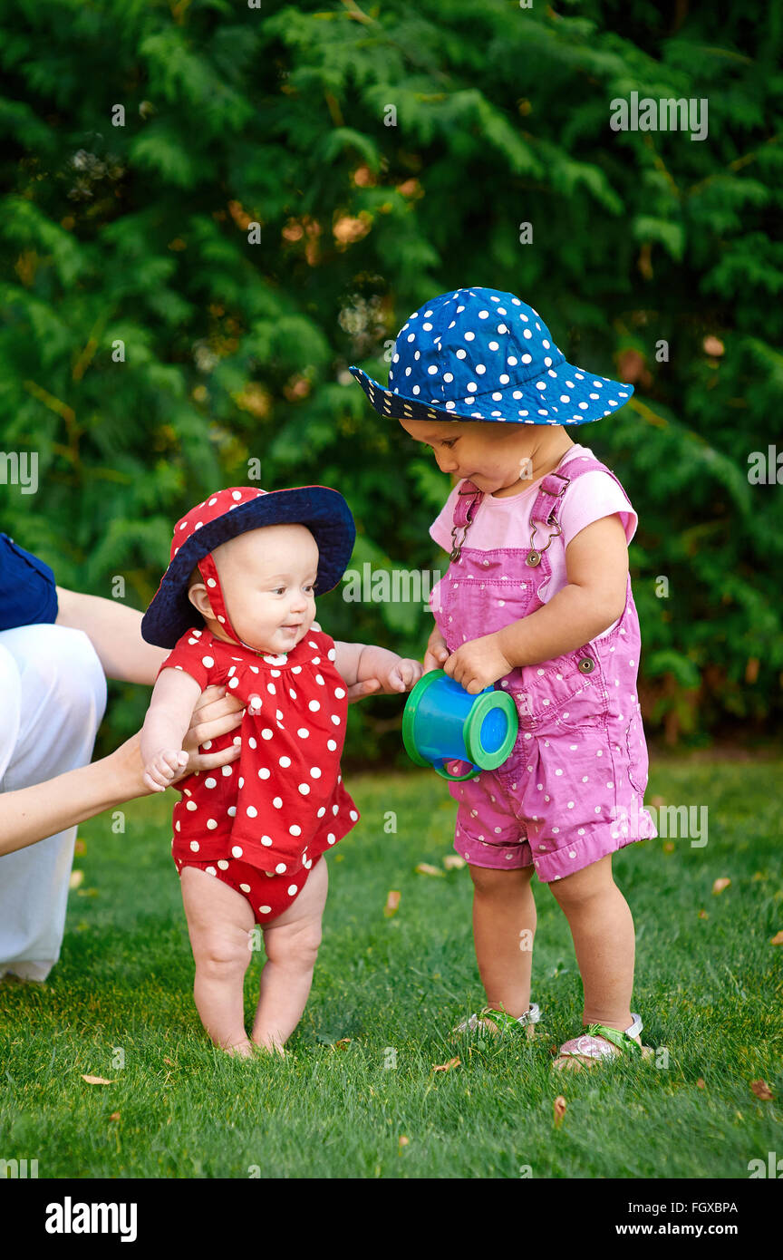 Two little girls playing on the green grass in spring garden Stock Photo