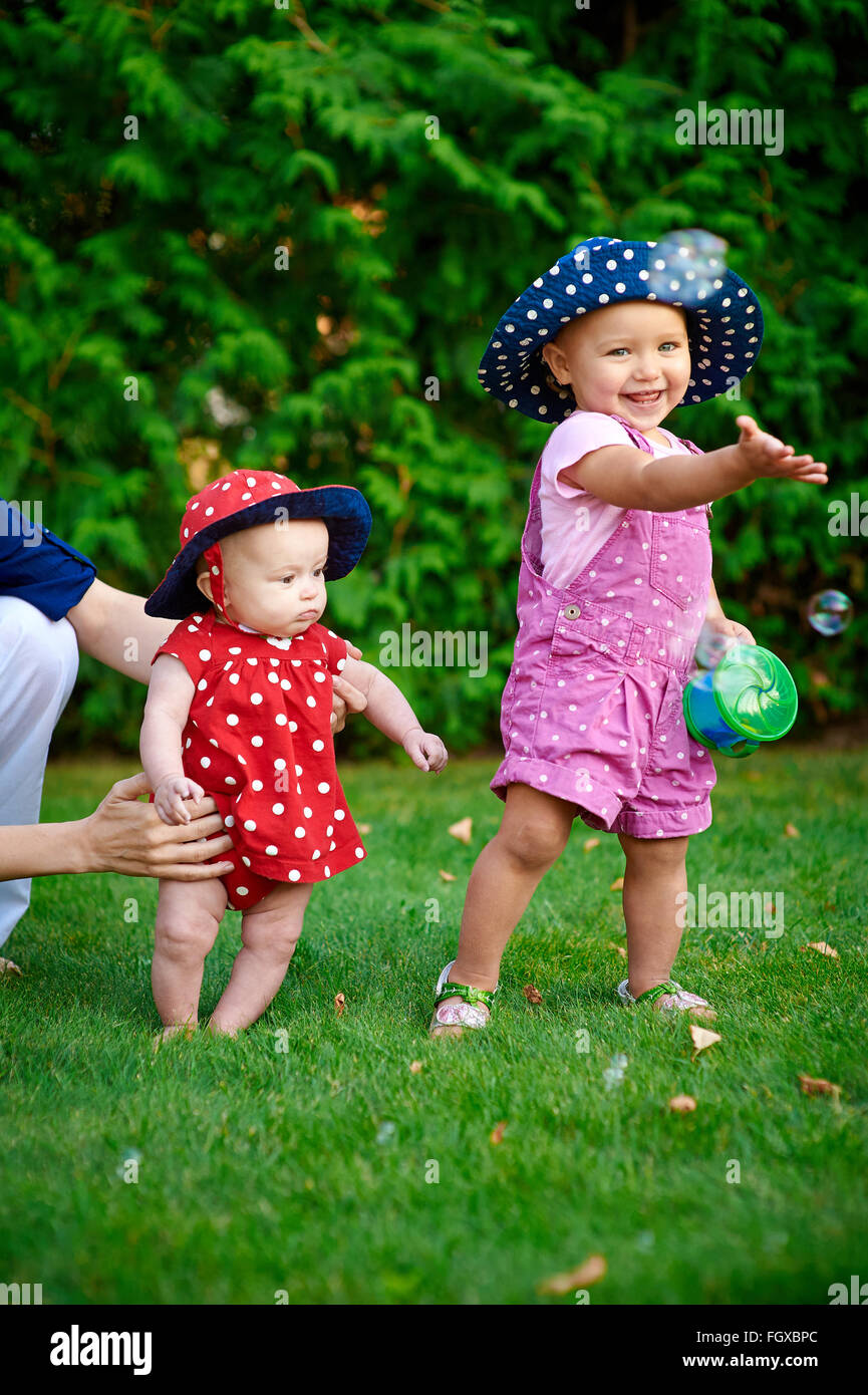 Two little girls playing on the green grass in spring garden Stock ...