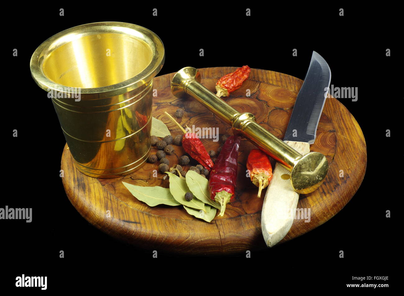 Brass mortar with pestle, knife and various spices lying on the cutting