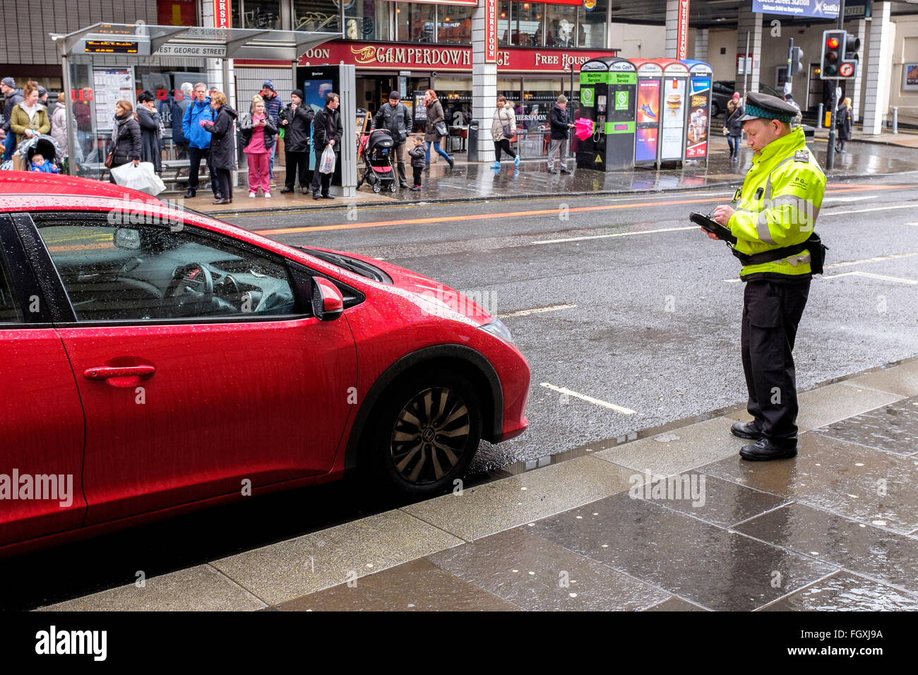 Traffic warden issuing a parking ticket to a car parked illegally in Glasgow city centre, Scotland, UK Stock Photo