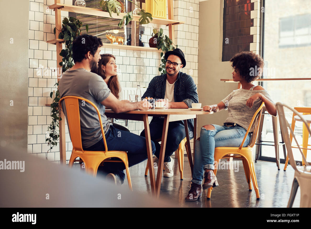Young people sitting at a cafe table. Group of friends talking in a coffee shop. Stock Photo