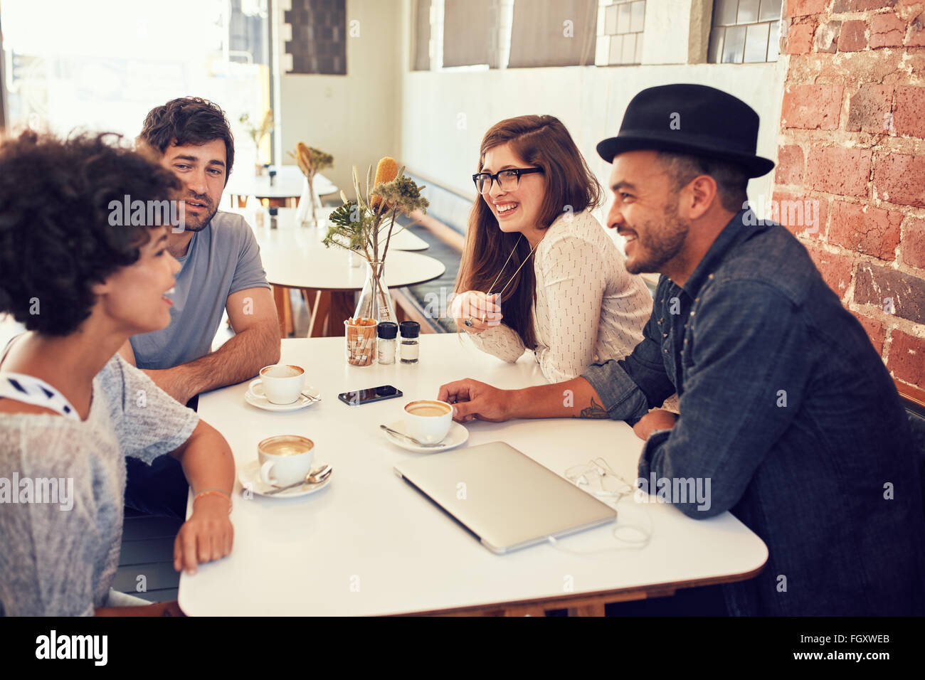 Group of young friends hanging out at a cafe. Young men and women sitting together and talking in a coffee shop. Stock Photo