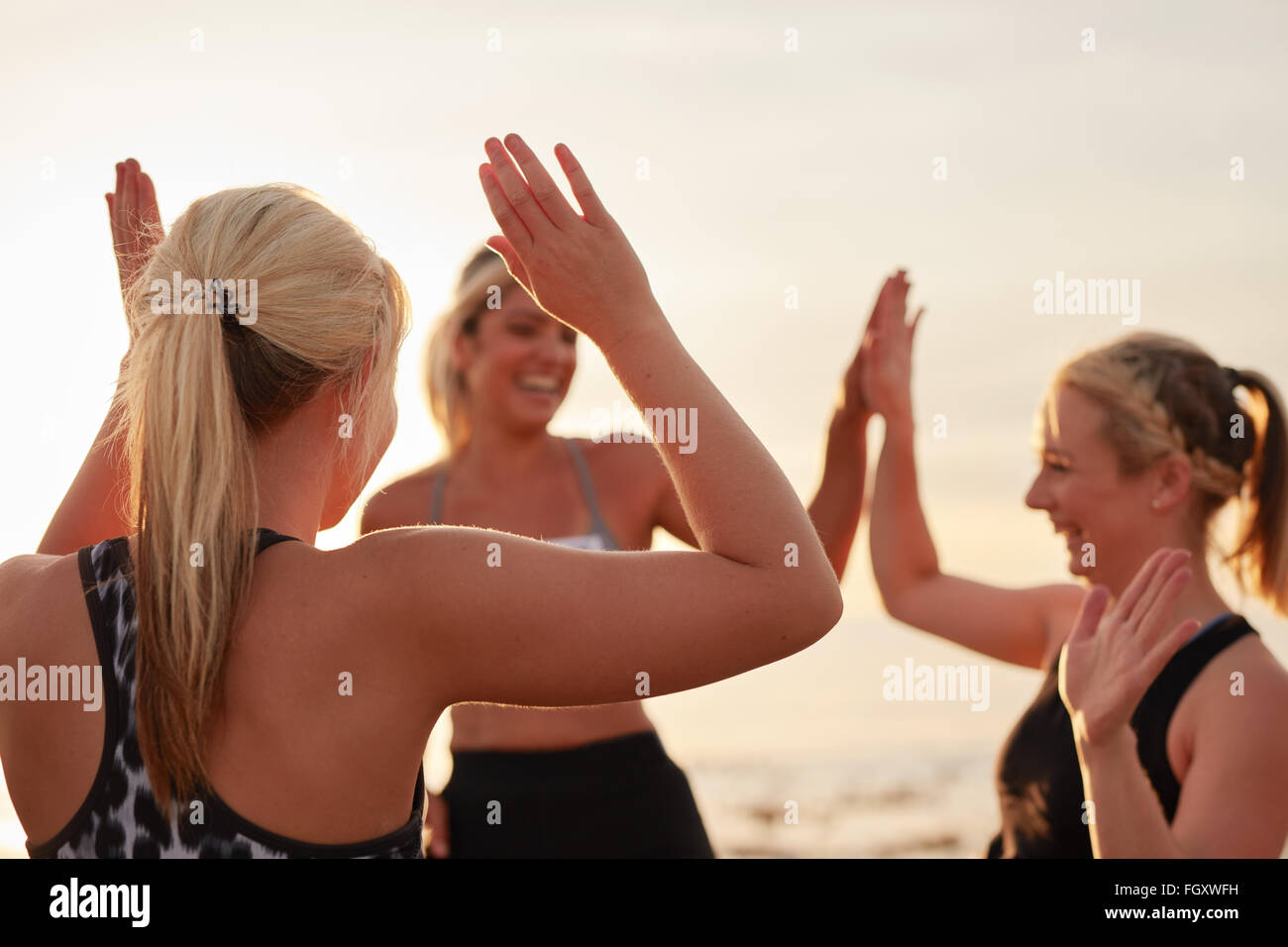 Runners giving high five to each other after a good training session. Group of athletes celebrating success. Stock Photo
