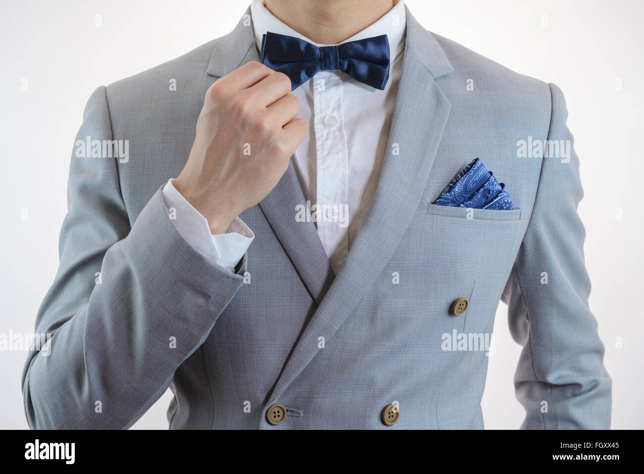 Man in grey suit, plaid texture, blue bowtie and pocket square, close up white background Stock Photo