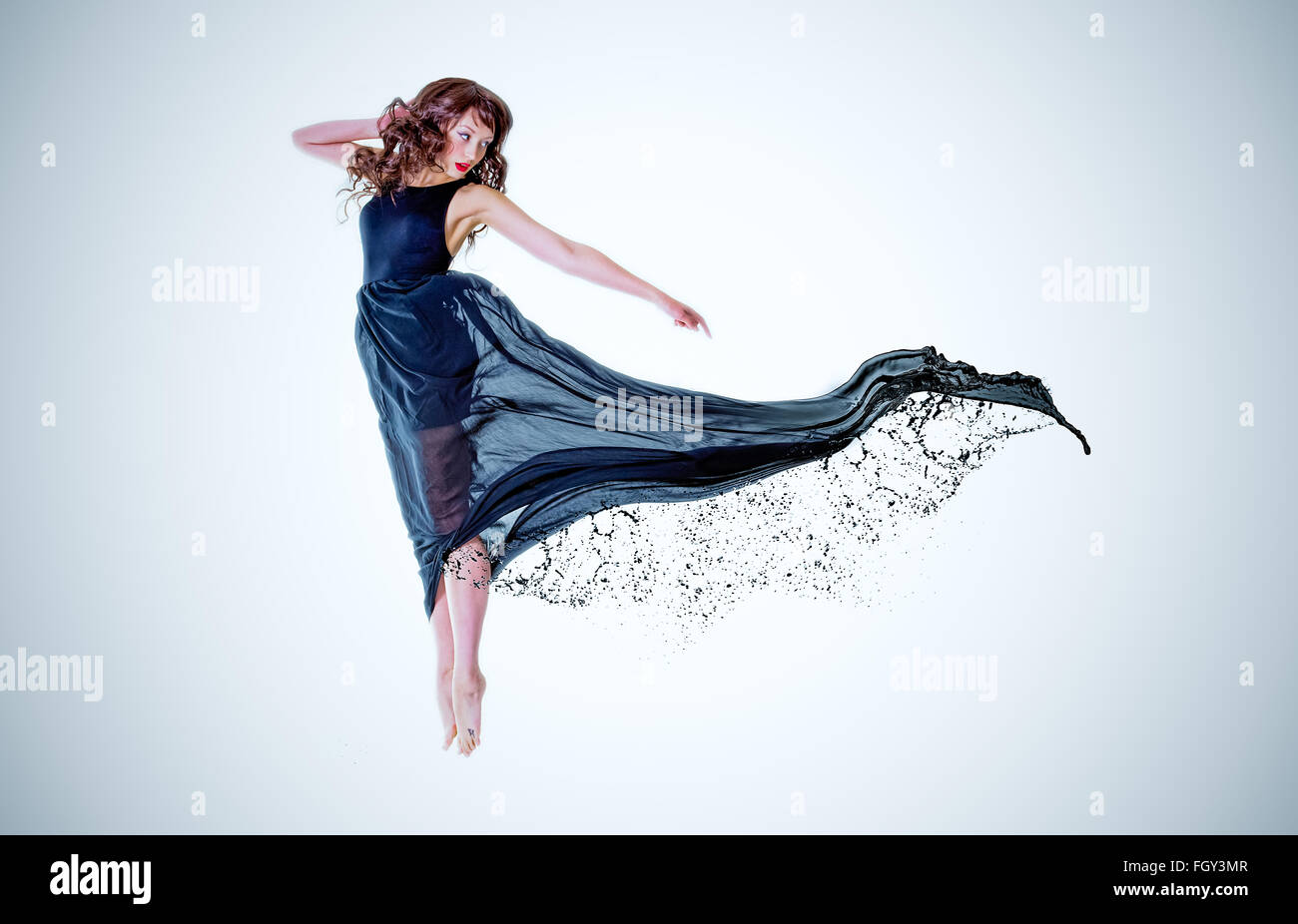 Young lady jumping in long black dress with oil dripping to the end Stock Photo