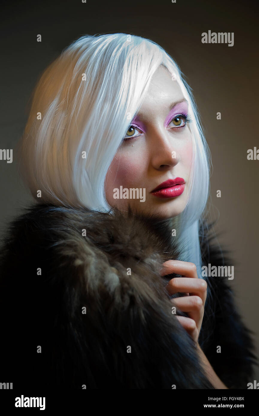 White haired lady wearing a fur coat with colorful make up Stock Photo