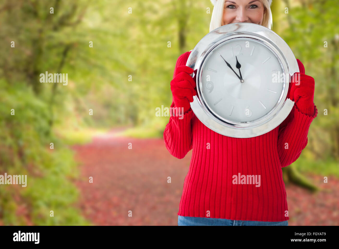 Composite image of happy festive blonde with clock Stock Photo
