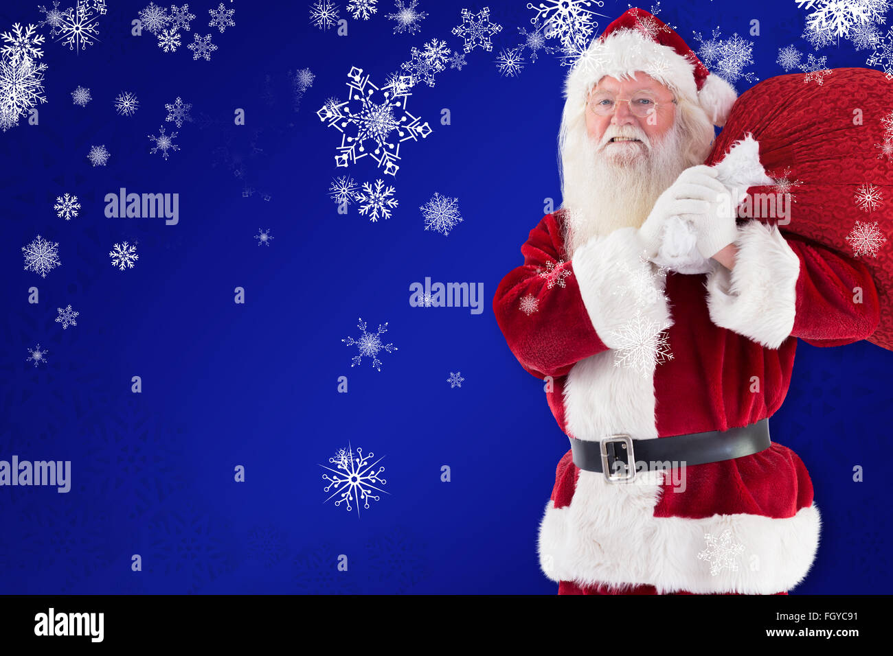 Composite image of santa carries his red bag and smiles Stock Photo - Alamy