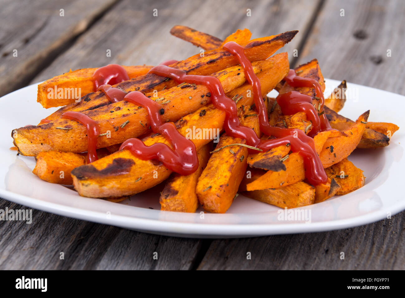 Sweet potato fries wedges closeup on wooden table with ketchup Stock Photo