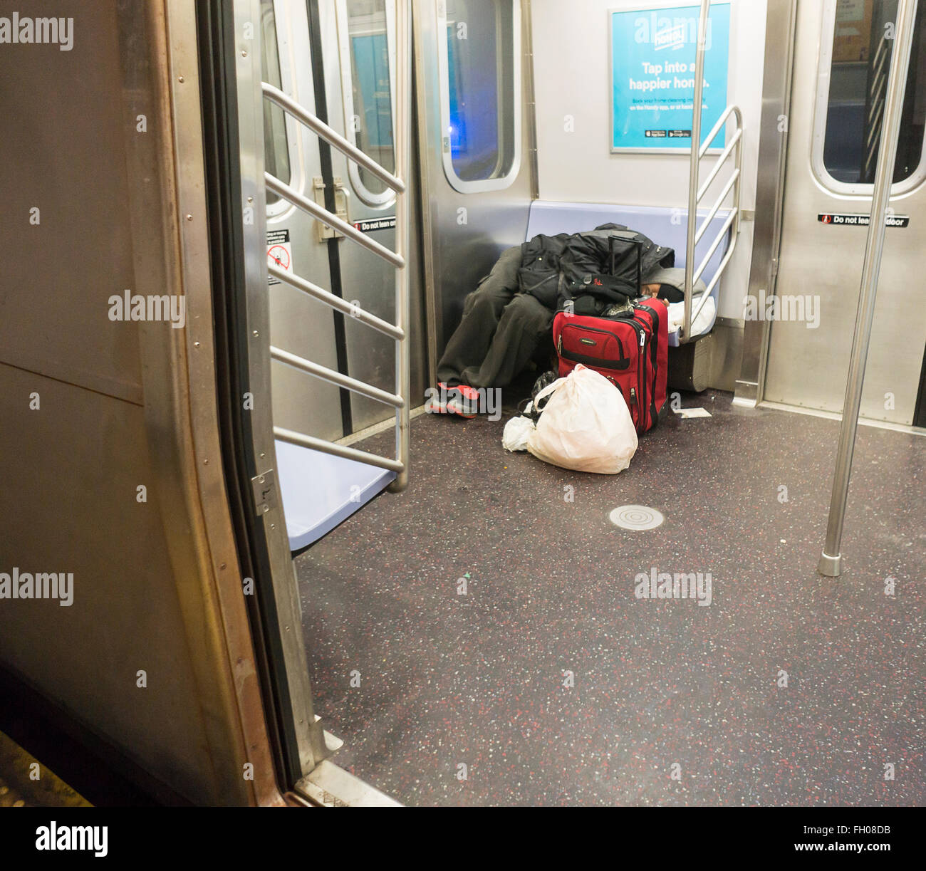 A homeless individual sleeps on the subway in New York on Wednesday ...